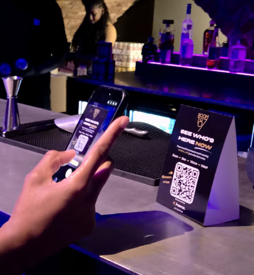 A guest scanning a branded I'm Here QR table card on a venue bar